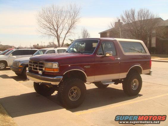 Maroon and tan Ford Bronco with lifted suspension and large tires parked in a lot