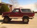 1992 Ford Bronco - Side view of a lifted 1992 Ford Bronco with a two-tone paint scheme and spare tire on the back.