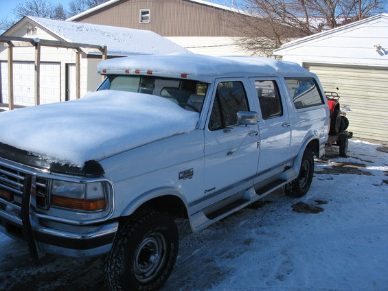 White extended cab pickup truck with camper shell, snow on hood and roof