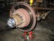 1995 Ford C-350 (Centurion Conversions) - Close-up of a vehicle's front wheel hub and brake assembly, supported by jack stands.