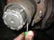 1995 Ford C-350 (Centurion Conversions) - Close-up view of a front axle hub assembly, showing a tool engaging with the locking mechanism during a rebuild.