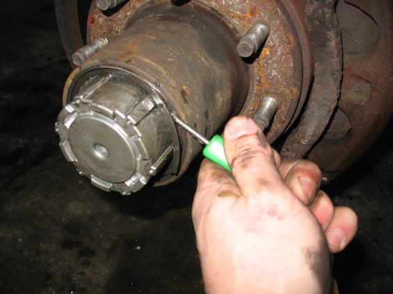Close-up of a front wheel hub assembly with a tool being used on the locking mechanism