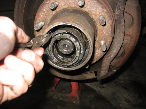 Close-up of a front wheel hub assembly with a hand using pliers on the locking mechanism