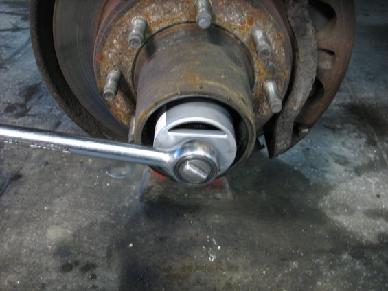 Close-up of a rusty wheel hub with a socket wrench attached to a nut