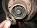 1995 Ford C-350 (Centurion Conversions) - Front wheel hub assembly with splines, a hand holds a greasy ring. Part of a brake rotor is visible.