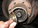 1995 Ford C-350 (Centurion Conversions) - A hand holds a removed bearing race from a heavily greased axle hub assembly.