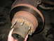 1995 Ford C-350 (Centurion Conversions) - Close-up view of a rusty front axle hub and rotor assembly, with a hand holding the hub.