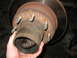1995 Ford C-350 (Centurion Conversions) - Close-up of a rusty front axle hub assembly, showing the bearing and brake rotor, likely during a rebuild.