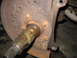 1995 Ford C-350 (Centurion Conversions) - Close-up of a heavily rusted wheel hub assembly, showing a splined axle shaft and a perforated brake rotor.