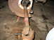 1995 Ford C-350 (Centurion Conversions) - Close-up of a rusty driveshaft U-joint and brake rotor assembly, supported by an orange jack stand.