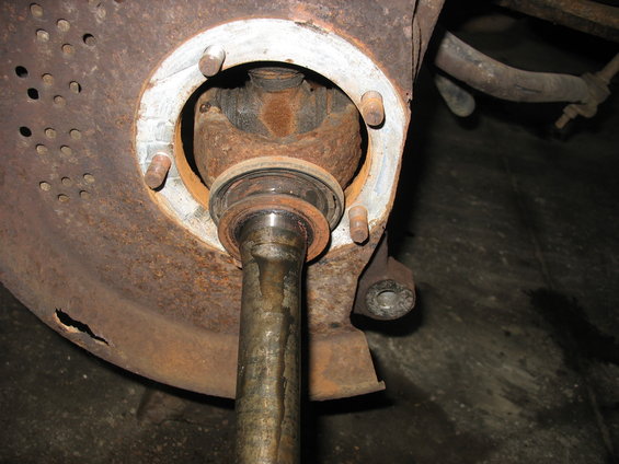Close-up of a rusty front axle assembly with a driveshaft entering a hub