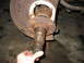 1995 Ford C-350 (Centurion Conversions) - Close-up of a heavily corroded front wheel hub and spindle assembly, likely requiring repair or replacement.