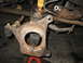 1995 Ford C-350 (Centurion Conversions) - Close-up of a heavily corroded vehicle front axle assembly, indicating a need for repair or completion of a rebuild.