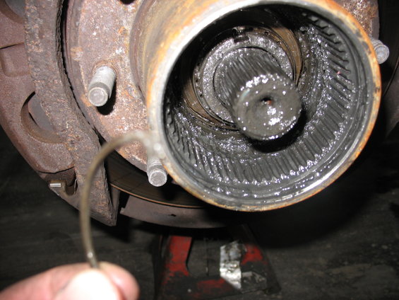 Close-up of a heavily greased, splined axle shaft inside a rusty hub assembly