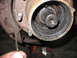 1995 Ford C-350 (Centurion Conversions) - A mechanic holds a bent metal clip near a disassembled front axle hub, revealing a splined shaft coated in old grease.