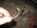 1995 Ford C-350 (Centurion Conversions) - A metal clip is held by a hand, with various tools and a red rag scattered on a concrete surface.