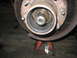 1995 Ford C-350 (Centurion Conversions) - The inner workings of a vehicle's front wheel hub are exposed, resting on a jack stand.