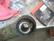 1995 Ford C-350 (Centurion Conversions) - Close-up of a worn suspension bushing on a rusty metal component, likely for a vehicle's front axle rebuild.