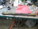1995 Ford C-350 (Centurion Conversions) - A single, heavily rusted suspension arm lies on a workbench, surrounded by tools and cleaning supplies.