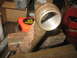 1995 Ford C-350 (Centurion Conversions) - A close-up view of a rusty, cylindrical metal part clamped in a vise, with a tape measure visible in the background.