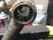 1995 Ford C-350 (Centurion Conversions) - This heavily corroded metal component is being held in a vise, showing significant damage and rust.