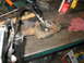 1995 Ford C-350 (Centurion Conversions) - A driveshaft U-joint is being worked on with tools on a cluttered workbench.