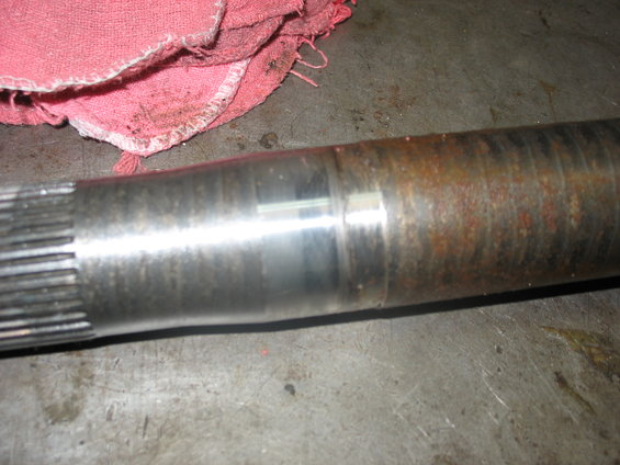 Close-up of a splined axle shaft with some rust and wear marks. A red shop rag is in the upper left