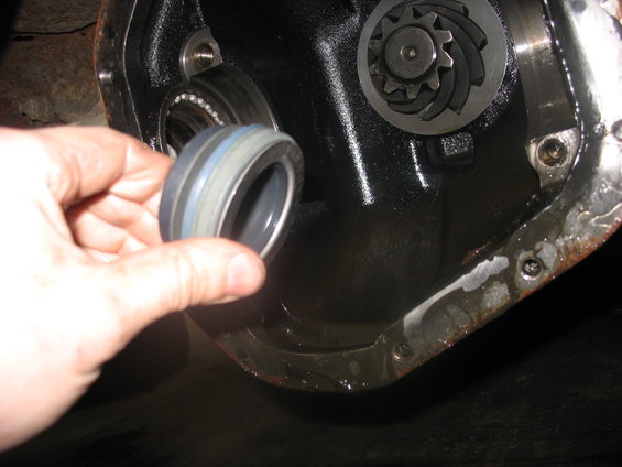 Hand holding a seal next to an open differential housing with gears visible