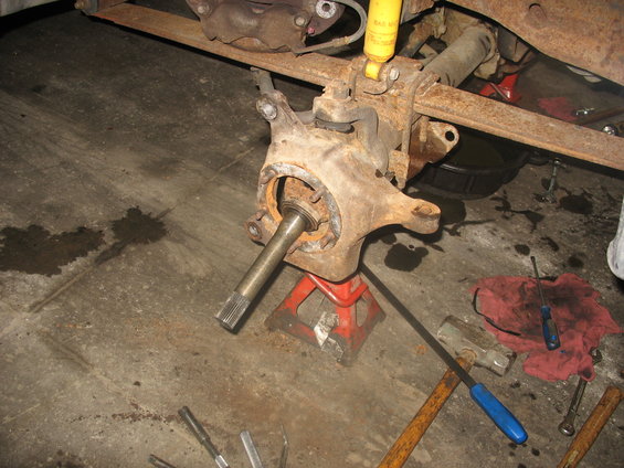 Front axle assembly on jack stands with tools on the floor