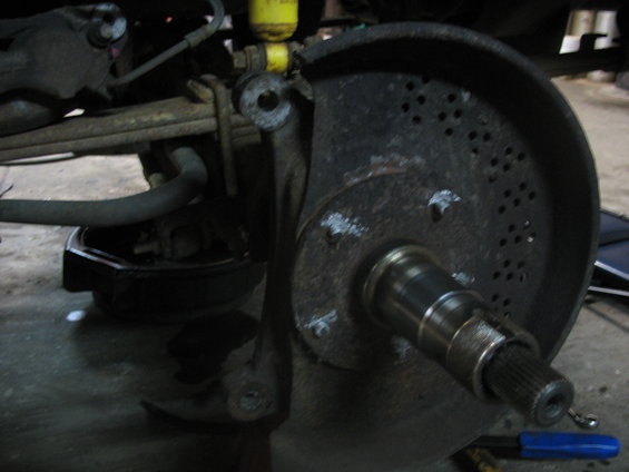 Vehicle's front axle assembly with brake rotor and hub. Shows suspension components and brake caliper mounting bracket