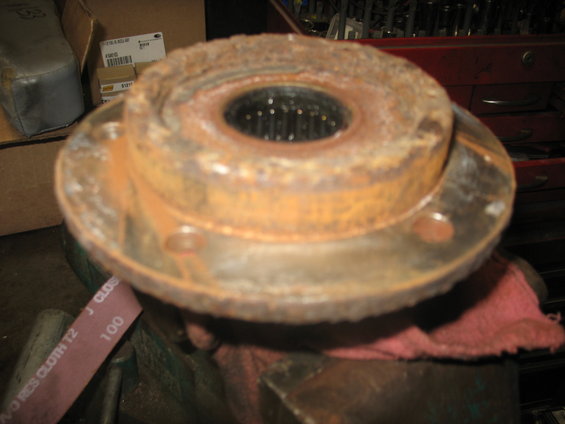 Rusted wheel hub assembly with splined center, held in a vise with a red cloth