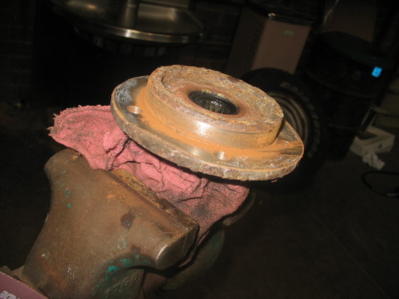 Rusted wheel hub assembly held in a vise with a red rag