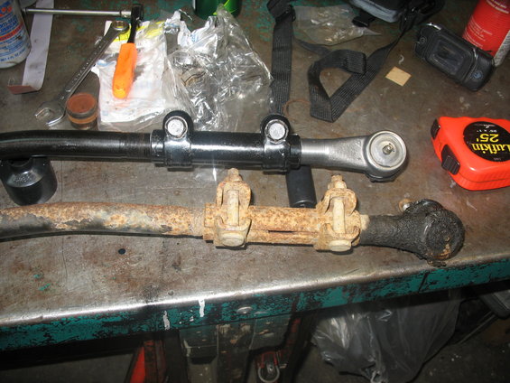 New black tie rod assembly above rusty old one. Tape measure visible