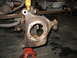 1995 Ford C-350 (Centurion Conversions) - Close-up of a rusty front axle knuckle, likely from a Ford C-350, undergoing repair.