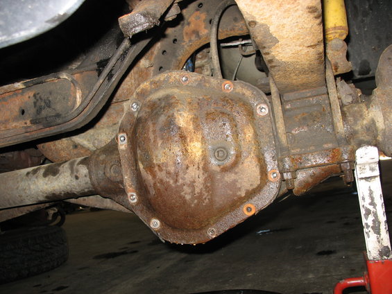 Rear axle differential cover with bolts, showing rust and some oil residue