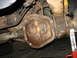 1995 Ford C-350 (Centurion Conversions) - Close-up of a rusty rear axle differential cover, likely needing service or replacement.