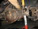 1995 Ford C-350 (Centurion Conversions) - Close-up view of the front axle and suspension components of a vehicle undergoing maintenance.