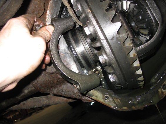 Close-up of differential gears and axle housing with a hand holding a part