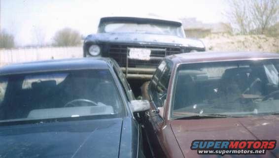 Front view of two sedans parked closely together, with a truck behind them
