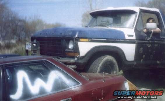 Ford truck with blue hood and white cab, parked next to a red car