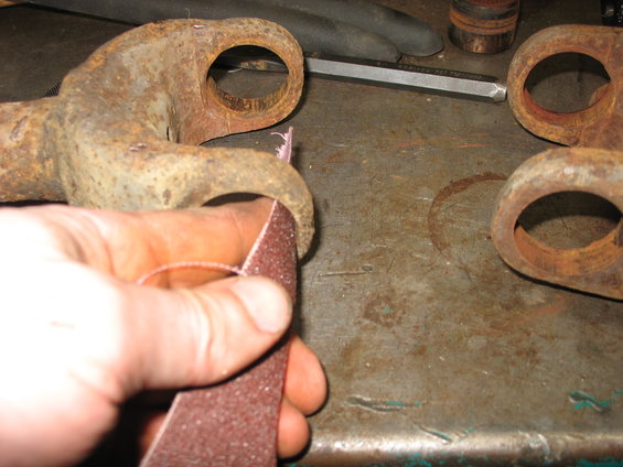 Hand sanding rusty metal components on a workbench