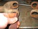 1995 Ford C-350 (Centurion Conversions) - Someone is cleaning up old, rusty metal parts with sandpaper on a workbench.