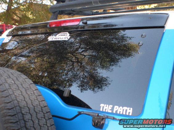 Back corner of a blue SUV, spare tire on the left, with a 'THE PATH' sticker on the rear window