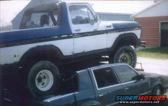 Lifted 1978 Ford Bronco on top of a dark sedan
