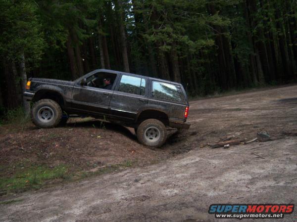 Black Ford Explorer off-roading on a dirt hill in a forest