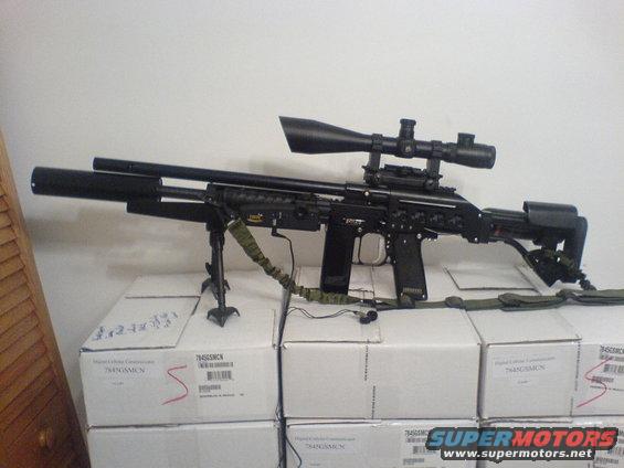 Black sniper rifle with scope and bipod resting on white boxes