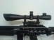 1985 Ford Bronco - A close-up view of a rifle equipped with a telescopic sight, against a plain background.