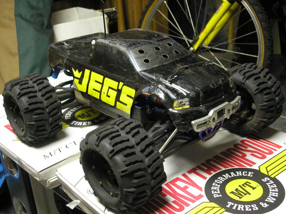 Black RC monster truck with yellow JEG'S lettering on side, sitting on boxes