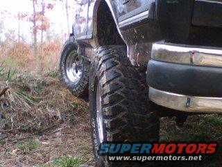 Close-up of a large off-road tire on a vehicle, with a chrome bumper visible