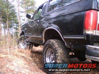 Black Ford Bronco with large Goodyear tires on a dirt road
